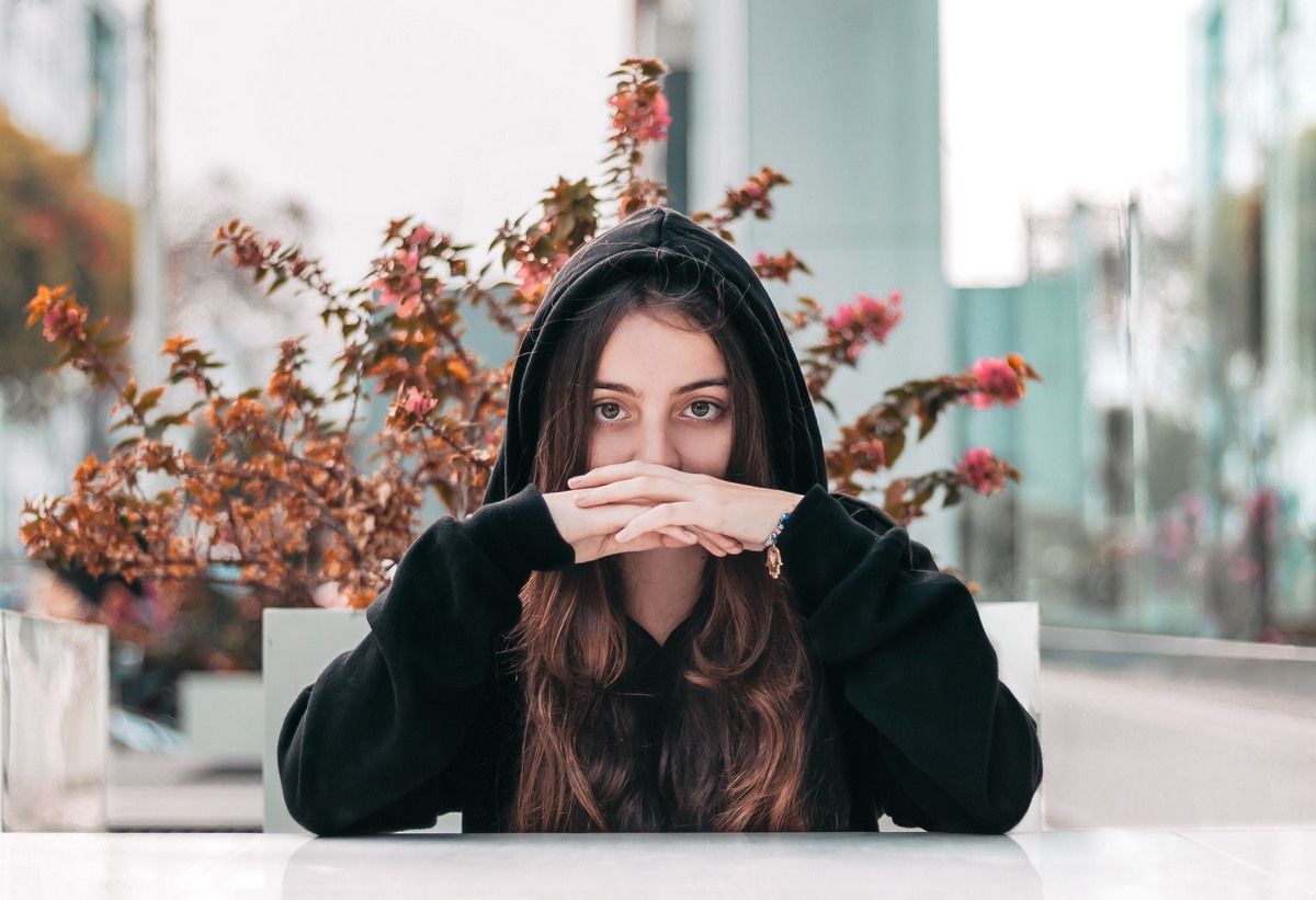 A Girl Wearing Hoddie Sitting On A Chair With Beautiful Backdrop