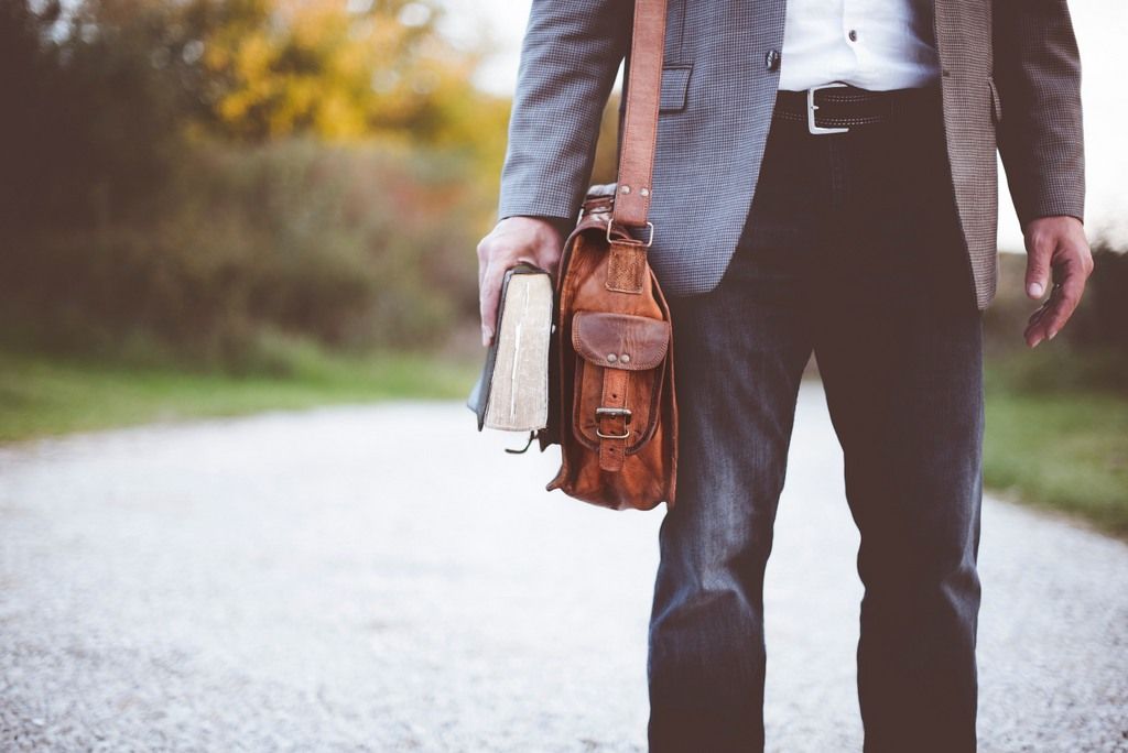 An Atheist Man Standing With A Book In Hand Wearing A Coat